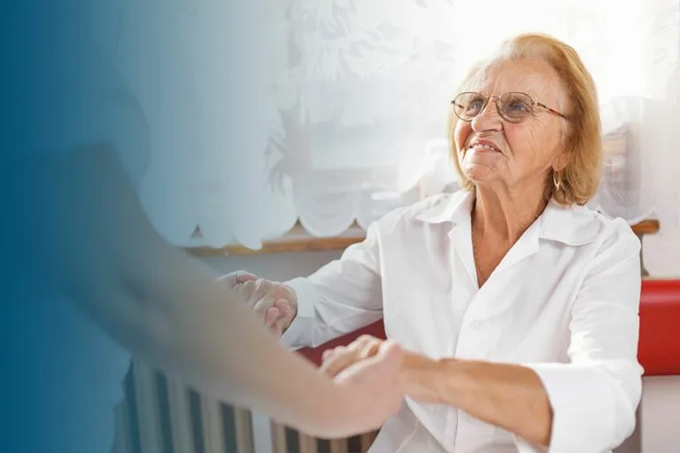 female carer holding hands and providing care for elderly woman