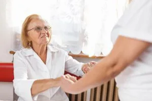 female carer holding hands and providing care for elderly woman sm