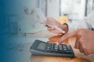 man using calculator holding receipts with cash and bills on table