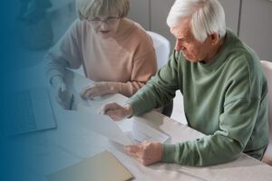 older couple sitting at table examining financial documents bl