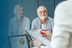 senior couple smiling at female consultant holding clip board in office