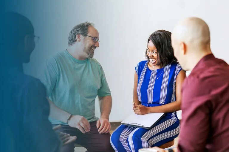 4 seated adults participating in community support group