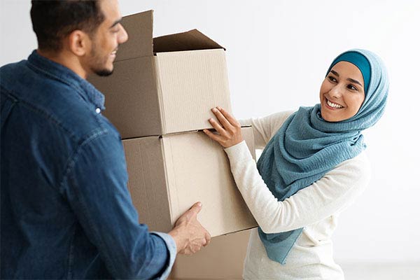 happy lady in hijab passing her husband moving boxes sm