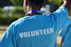 african american volunteer wearing blue t shirt with volunteer text printed on back