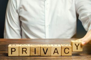 privacy spelled using wooden blocks aligned in row infront of man in white shirt